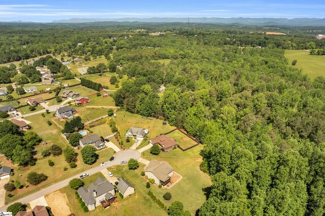 aerial view of property and surrounding area with a heavily wooded area and a mountain backdrop