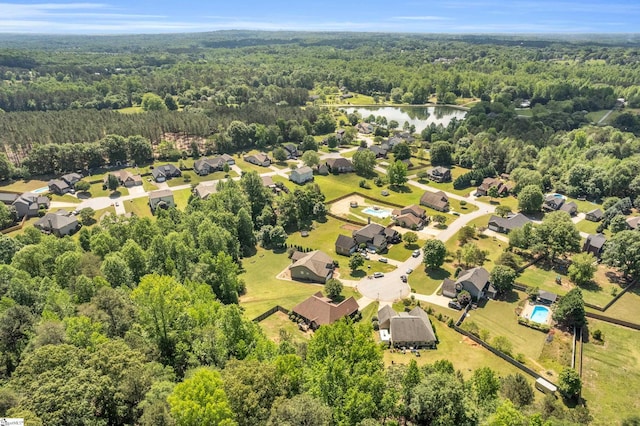 aerial view of residential area featuring a heavily wooded area and a nearby body of water