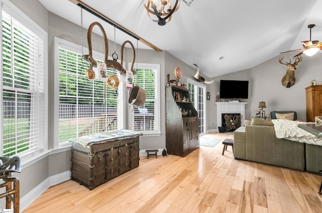 living room featuring healthy amount of natural light, hardwood / wood-style floors, a ceiling fan, a fireplace, and vaulted ceiling