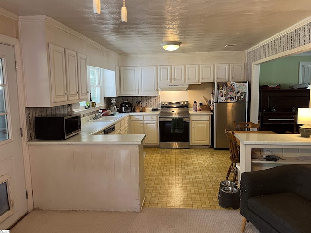 kitchen featuring stainless steel appliances, under cabinet range hood, a sink, light countertops, and a peninsula