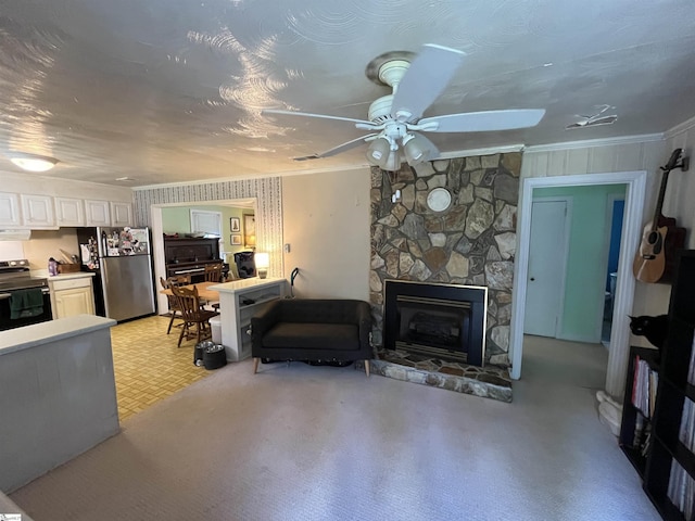 living room featuring a ceiling fan, crown molding, and a stone fireplace
