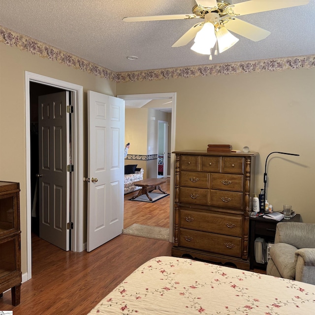 bedroom with dark wood-style flooring, a textured ceiling, and a ceiling fan