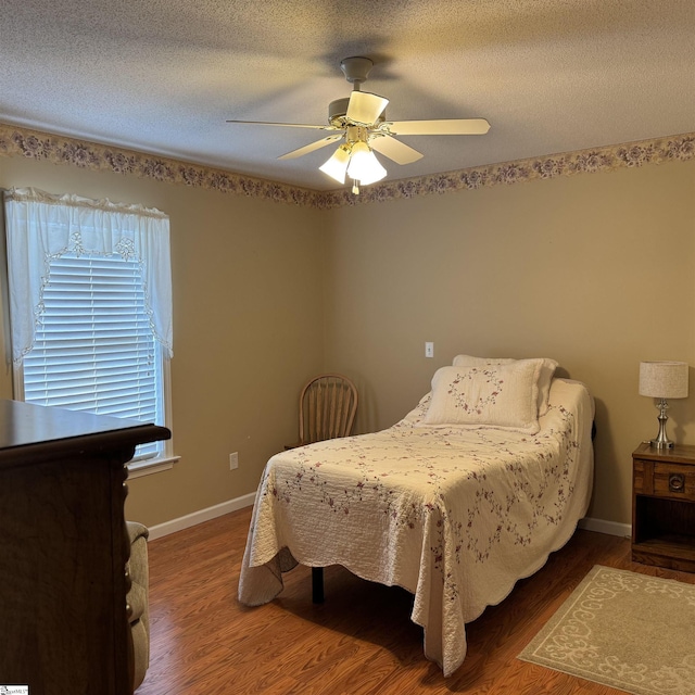 bedroom featuring wood finished floors, baseboards, a ceiling fan, and a textured ceiling