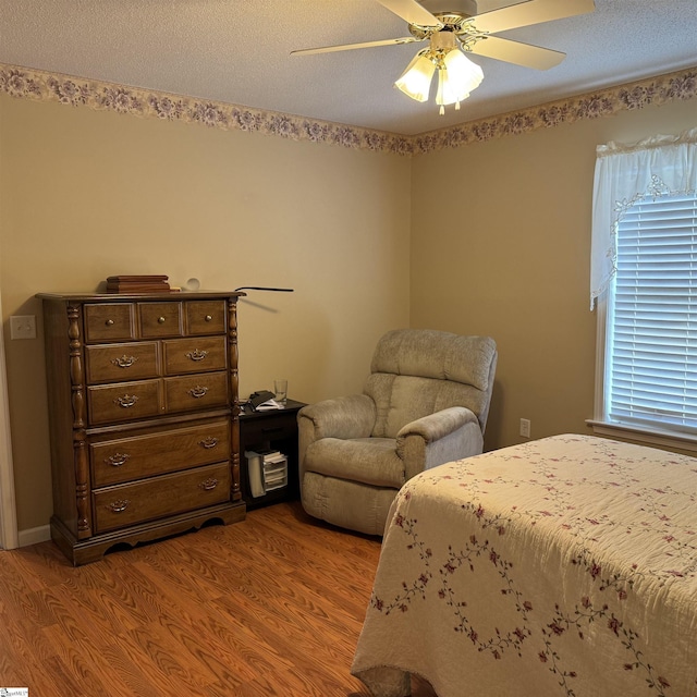 bedroom featuring wood finished floors, a ceiling fan, and a textured ceiling