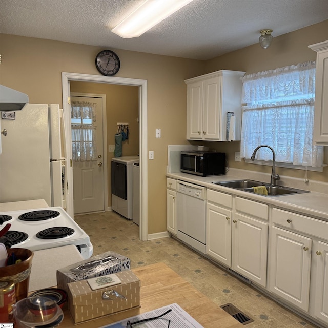 kitchen with white appliances, a sink, washer and clothes dryer, healthy amount of natural light, and a textured ceiling