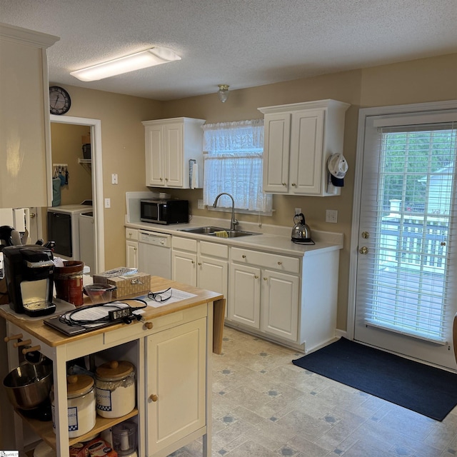 kitchen with a sink, white dishwasher, white cabinets, a textured ceiling, and washing machine and clothes dryer