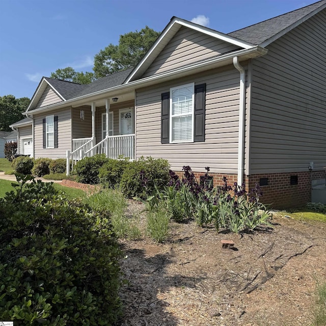 ranch-style home with covered porch, crawl space, roof with shingles, and a garage