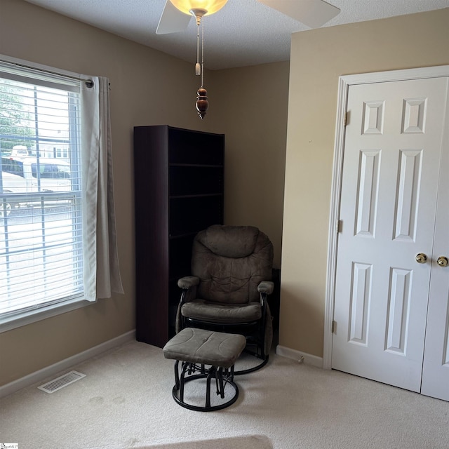 sitting room featuring healthy amount of natural light, ceiling fan, carpet flooring, and baseboards
