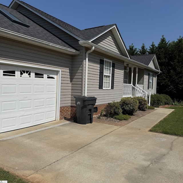 view of home's exterior with roof with shingles and driveway