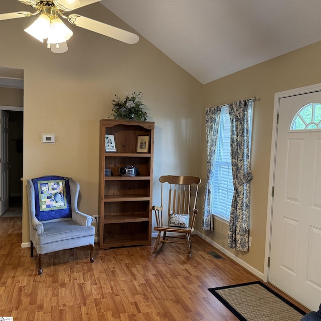 living area with light wood finished floors, vaulted ceiling, ceiling fan, and baseboards