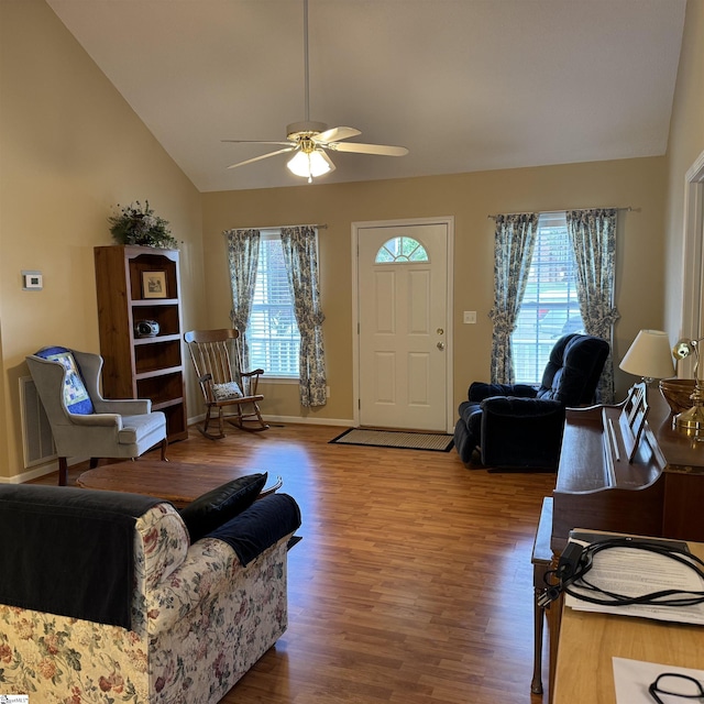 living area featuring vaulted ceiling, healthy amount of natural light, wood finished floors, and a ceiling fan