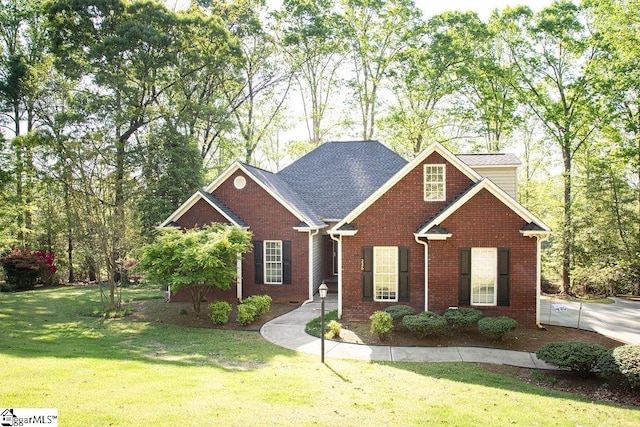 traditional-style home featuring a front yard, brick siding, and a shingled roof