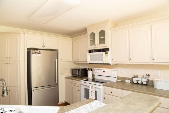 kitchen with white appliances, glass insert cabinets, white cabinetry, and a sink