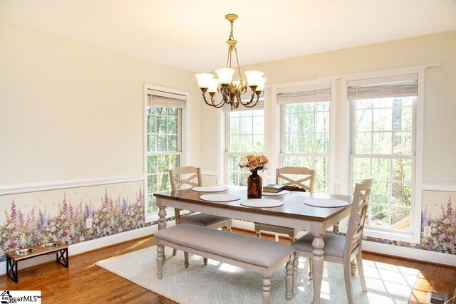 dining space featuring a chandelier, wood finished floors, and baseboards
