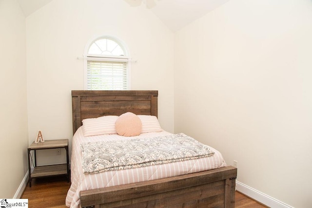 bedroom with lofted ceiling, wood finished floors, and baseboards