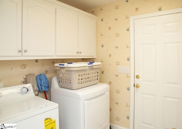laundry area featuring washing machine and dryer, wallpapered walls, and cabinet space