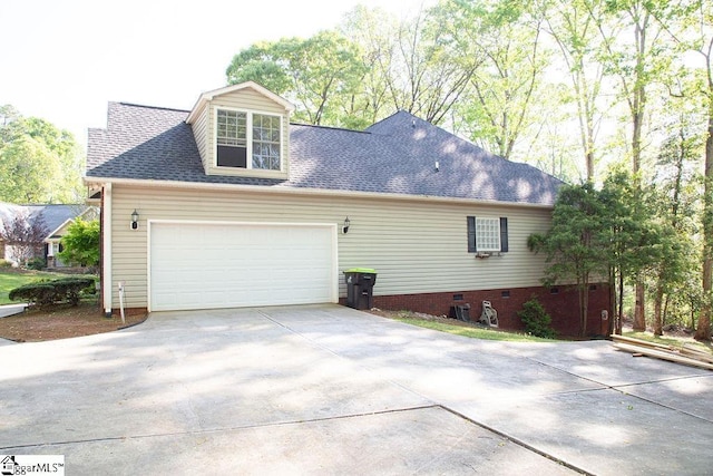 view of side of home featuring driveway, a shingled roof, an attached garage, and crawl space