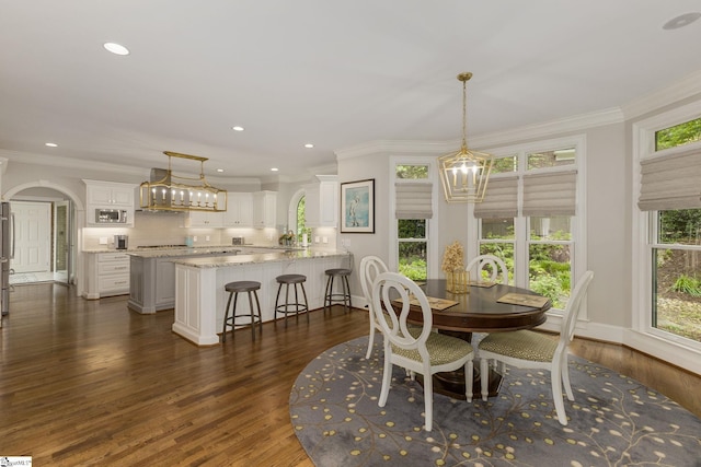 dining area featuring dark wood-style floors, a chandelier, ornamental molding, recessed lighting, and arched walkways