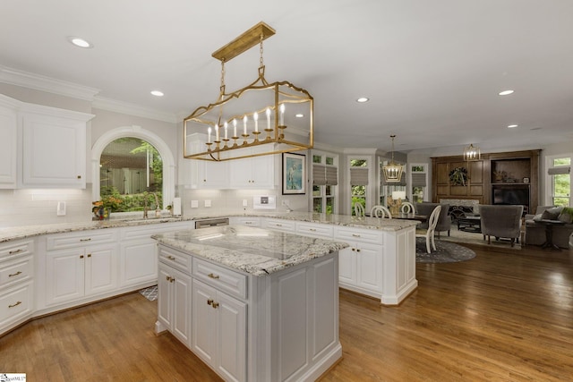 kitchen with a kitchen island, a peninsula, crown molding, open floor plan, and backsplash