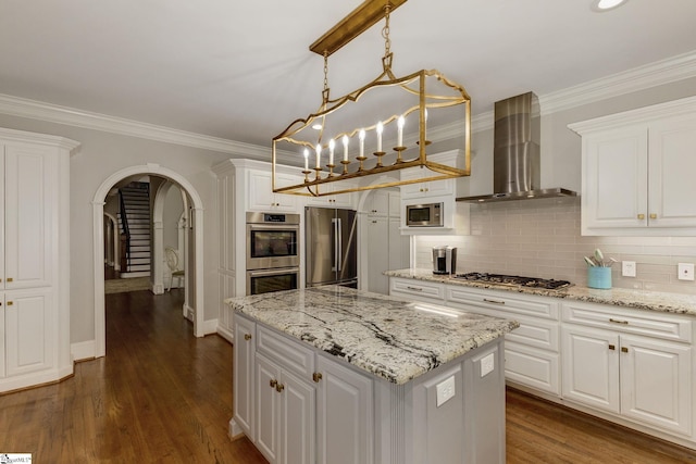 kitchen featuring stainless steel appliances, wall chimney range hood, arched walkways, white cabinetry, and crown molding