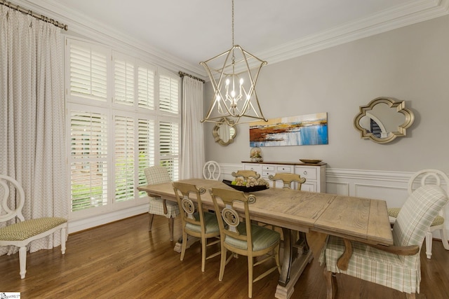 dining room with a chandelier, ornamental molding, wood finished floors, wainscoting, and a decorative wall