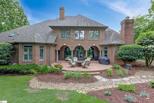 back of property featuring a chimney, brick siding, a patio, and a yard