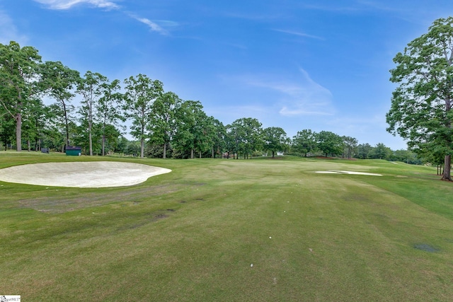 surrounding community featuring view of wooded area, view of golf course, and a lawn