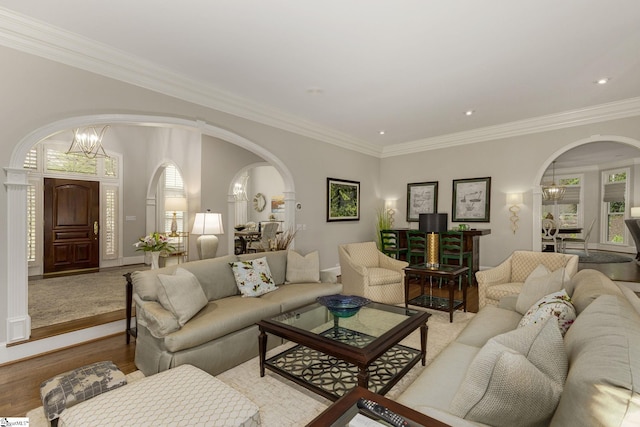 living room featuring arched walkways, crown molding, baseboards, light wood-type flooring, and recessed lighting