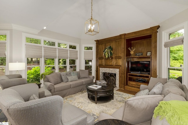 living room with a chandelier, high vaulted ceiling, a fireplace with flush hearth, and wood finished floors