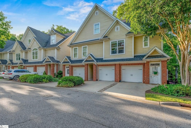 multi unit property with driveway, brick siding, an attached garage, and a shingled roof