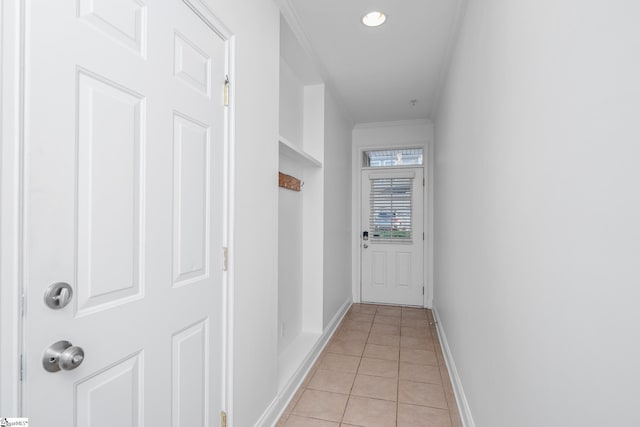 corridor featuring light tile patterned floors, baseboards, and crown molding