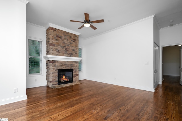 unfurnished living room featuring ceiling fan, wood finished floors, crown molding, a stone fireplace, and baseboards