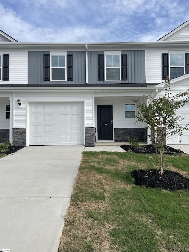 view of front of house featuring stone siding, board and batten siding, driveway, and a garage
