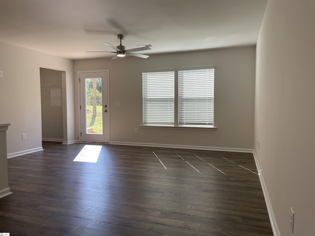 unfurnished living room featuring a ceiling fan, dark wood-type flooring, and baseboards