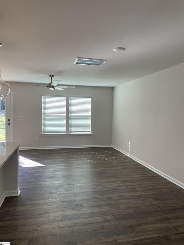 empty room featuring dark wood-type flooring, baseboards, and ceiling fan