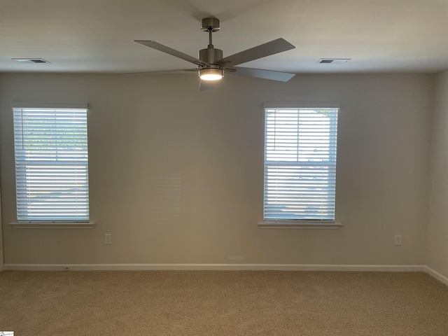 spare room with light carpet, ceiling fan, and baseboards