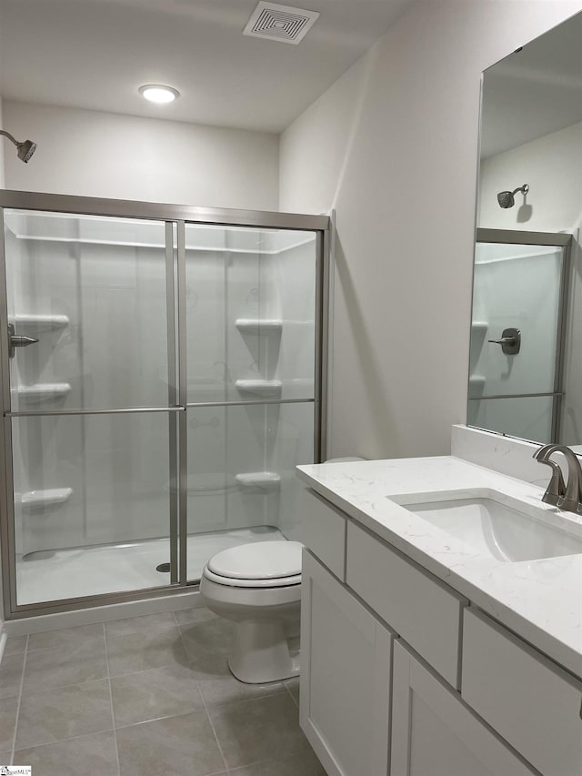 full bath with a shower stall, toilet, vanity, and tile patterned floors