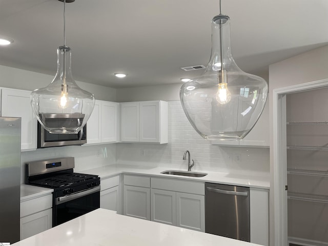 kitchen featuring appliances with stainless steel finishes, a sink, light countertops, tasteful backsplash, and hanging light fixtures