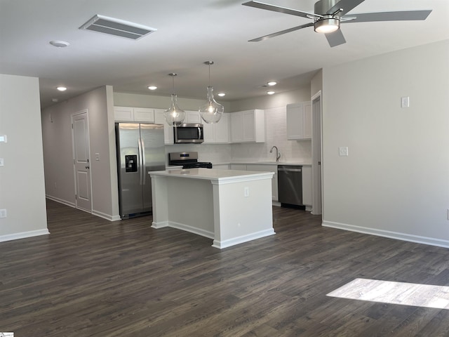 kitchen featuring appliances with stainless steel finishes, recessed lighting, a kitchen island, dark wood-style flooring, and light countertops