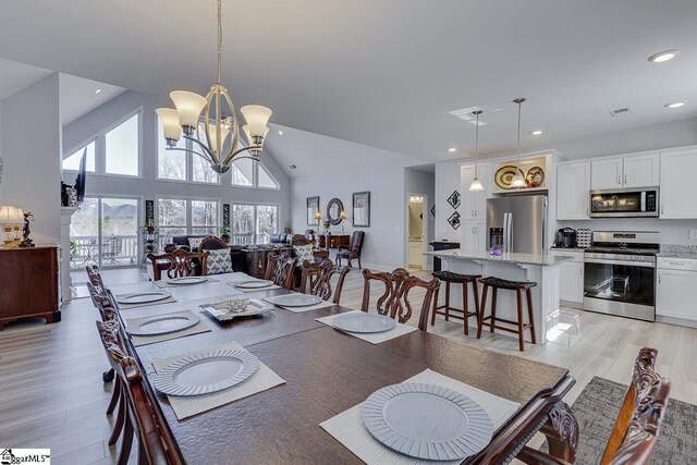 dining room featuring a chandelier, light wood finished floors, recessed lighting, and vaulted ceiling