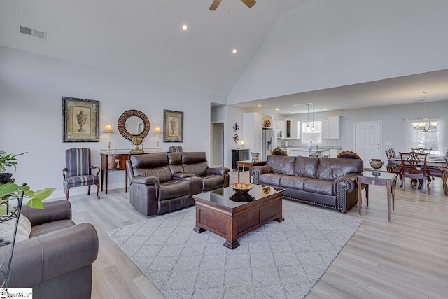 living room featuring a ceiling fan, a chandelier, light wood-style flooring, high vaulted ceiling, and recessed lighting
