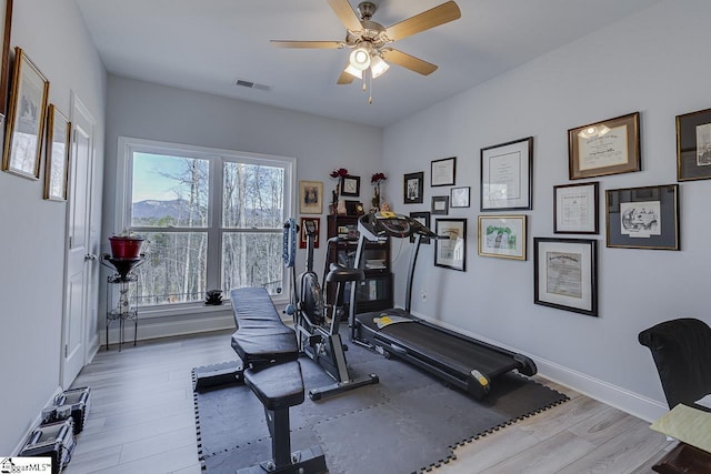 exercise area with wood finished floors, a ceiling fan, and baseboards