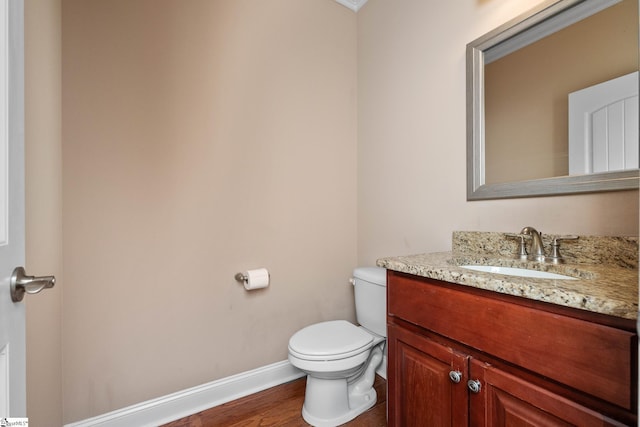 bathroom featuring toilet, baseboards, vanity, and wood finished floors