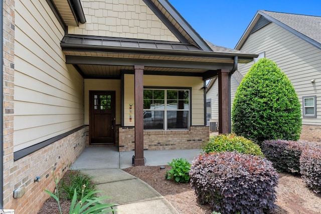 property entrance featuring covered porch and brick siding