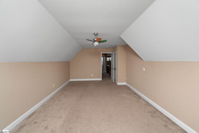 bonus room featuring vaulted ceiling, a ceiling fan, light colored carpet, and baseboards