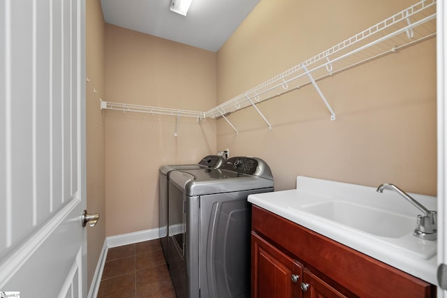 washroom featuring washing machine and dryer, cabinet space, baseboards, and dark tile patterned flooring