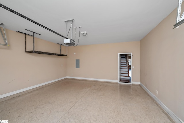 garage featuring a garage door opener, baseboards, and electric panel