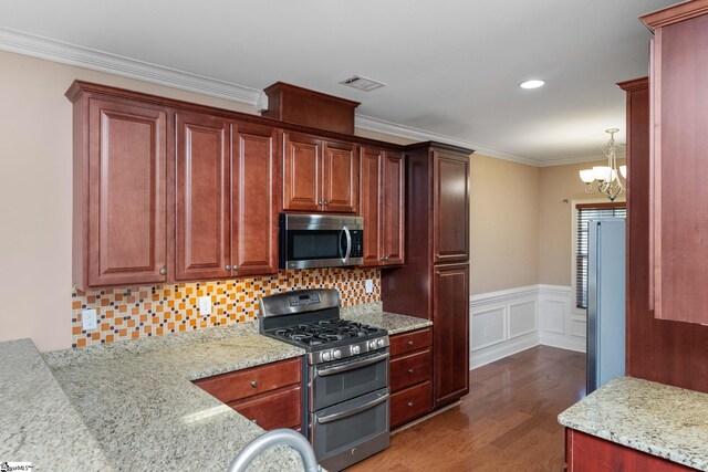 kitchen with appliances with stainless steel finishes, dark wood finished floors, a chandelier, ornamental molding, and backsplash