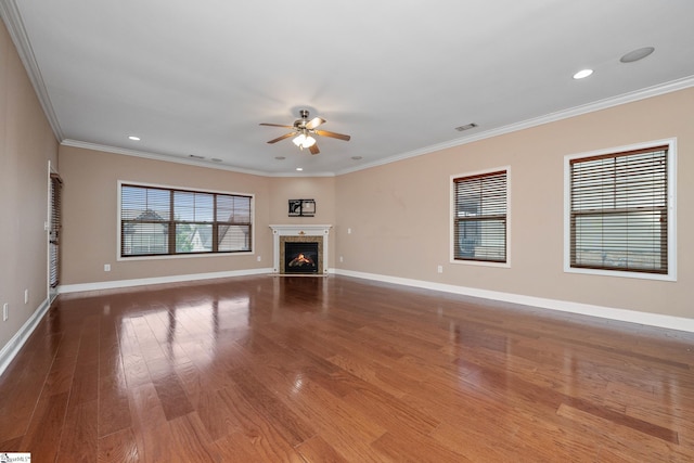unfurnished living room with ceiling fan, wood finished floors, baseboards, ornamental molding, and a fireplace with flush hearth