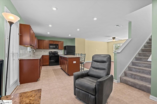 kitchen featuring black appliances, open floor plan, a center island, decorative backsplash, and a sink